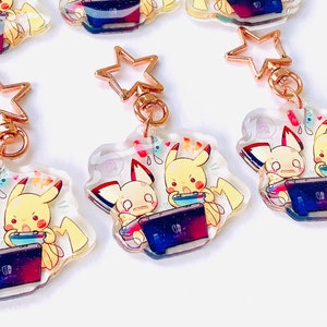 Pikachu y Pichu Tocando Amuletos de Interruptor (Acrílico Transparente de 2 pulgadas)