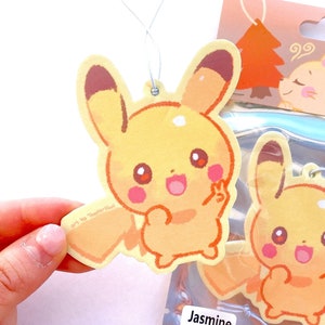 May include: Yellow air fresheners featuring a cartoon character with a smiling face and a peace sign. The air fresheners are packaged in a clear plastic bag with the words "Air Freshener" and "Jasmine" printed on the packaging.