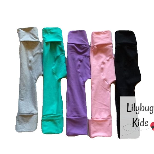 May include: Five pairs of children's leggings in different colors: gray, teal, purple, pink, and black. The leggings are folded and arranged in a row. The text "Lilybug Kids" is visible in the lower right corner of the image.