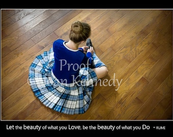 May include: A person wearing a blue top and a blue and white plaid skirt, sitting on a wooden floor. The image includes the text "Proof on Kennedy" and a quote by Rumi.