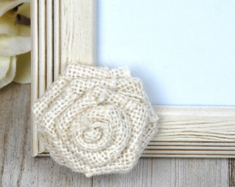 May include: A white picture frame with a burlap rose embellishment. The frame is distressed and has a rustic look.