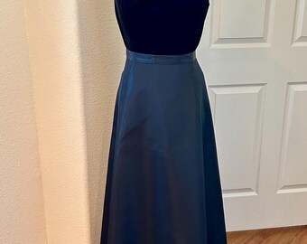 Könnte beinhalten: Ein schwarzes trägerloses Abendkleid mit einem Samt-Oberteil und einem Satinrock. Das Kleid befindet sich auf einer Schaufensterpuppe und wird vor einem hellen Holzboden fotografiert.