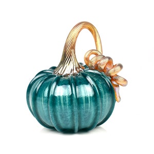 May include: A teal glass pumpkin with a gold and amber glass stem and a twisted stem detail.