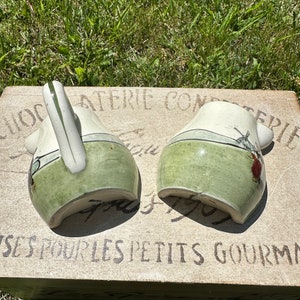 May include: Two green and white ceramic pitchers with a windmill design and the text "ATERIE CONFEPTURES POUR LES PETITS GOURMANDS" on the base.