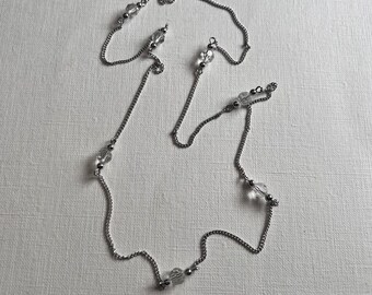 Könnte beinhalten: Eine silberne Kettenkette mit klaren Kristallperlen. Die Kette ist geschichtet und hat eine zarte Kette.