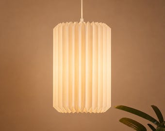 May include: A cylindrical pendant light fitting featuring a white, vertically pleated shade that emits a soft, warm glow. The lamp is suspended from a thin, white cord, creating a clean, uniform appearance with sharp, vertical folds.