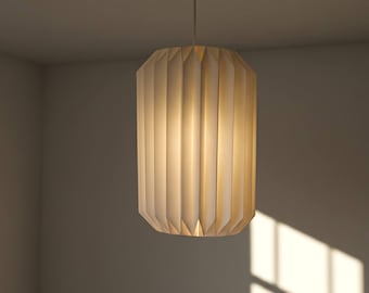 May include: A cylindrical pendant light fixture featuring a pleated, off-white paper shade. The structure consists of vertical folds that create a textured, accordion-like appearance, emitting a soft, warm glow from within the center.