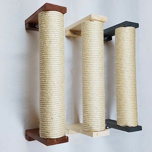 Könnte beinhalten: Drei wandmontierte Kratzbäume für Katzen mit verschiedenen farbigen Sockeln. Die Pfosten sind mit natürlichem Sisal-Seil umwickelt und an Holz- und schwarzen Metallhalterungen befestigt.