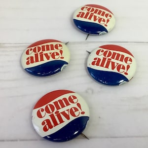 May include: Four round, red, white, and blue buttons with the text "come alive!" in red letters.