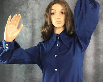 May include: A navy blue long-sleeved shirt with a large collar and button closure. The shirt has puffed sleeves and a slightly fitted silhouette.