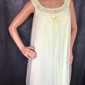 May include: A pale yellow, sheer, sleeveless nightgown with a ruffled neckline and a satin bow at the center.