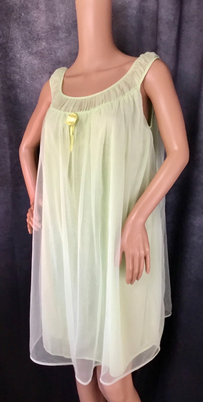 May include: A pale green sheer nightgown with a gathered neckline and a yellow satin bow.