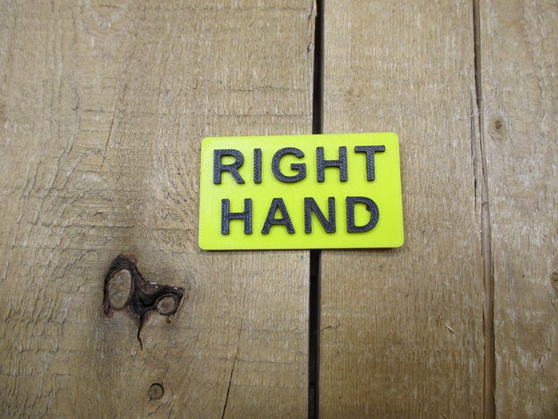 May include: A rectangular, neon yellow sign with the words "RIGHT HAND" in bold, black capital letters. The sign is set against a backdrop of weathered, light brown wooden planks.