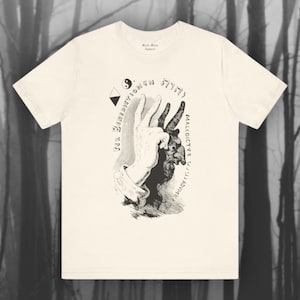 Könnte beinhalten: Ein weißes T-Shirt mit einer Schwarzweißillustration einer Hand mit einem Schatten eines Ziegenkopfes. Der Text "MALEDICTUS" und "PER BENEDICTIONEM" ist um das Bild herum geschrieben. Der Text "5777" ist über dem Bild geschrieben.