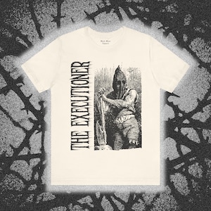 May include: A cream-colored short-sleeve t-shirt featuring a black ink-style graphic of a hooded figure holding an axe. The text THE EXECUTIONER is printed vertically in a stylized font next to the illustration, with Black Mass Apparel on the neck.