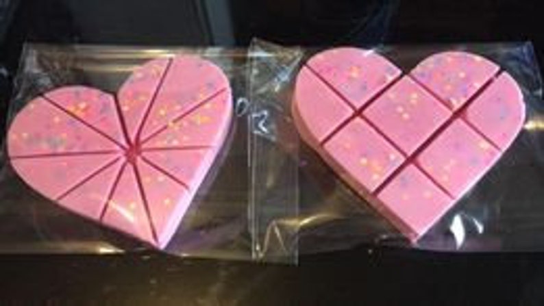 Op de afbeelding: Twee roze hartvormige wax melts met glitter, elk verdeeld in 12 secties.