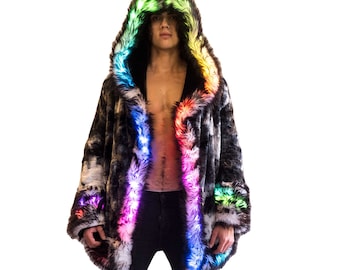 May include: A black and white faux fur coat with a rainbow LED trim. The coat has a hood and is worn by a person standing in front of a white background.