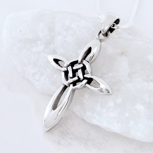 May include: A silver Celtic knot cross pendant necklace. The cross is made of interwoven knots and has a smooth, polished finish.
