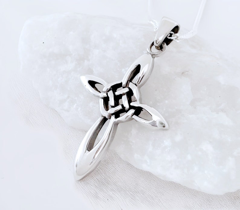 May include: A silver Celtic knot cross pendant necklace. The cross is made of interwoven knots and has a smooth, polished finish.