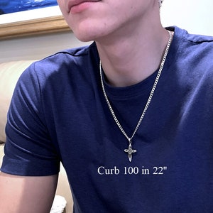 May include: A silver curb chain necklace with a silver cross pendant. The chain is 22 inches long and the text "Curb 100 in 22" is printed on a blue t-shirt.