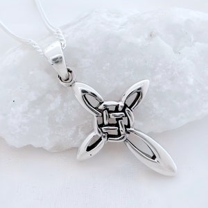 May include: Silver Celtic knot cross pendant necklace. The cross is made of a woven knot design with a smooth, polished finish.