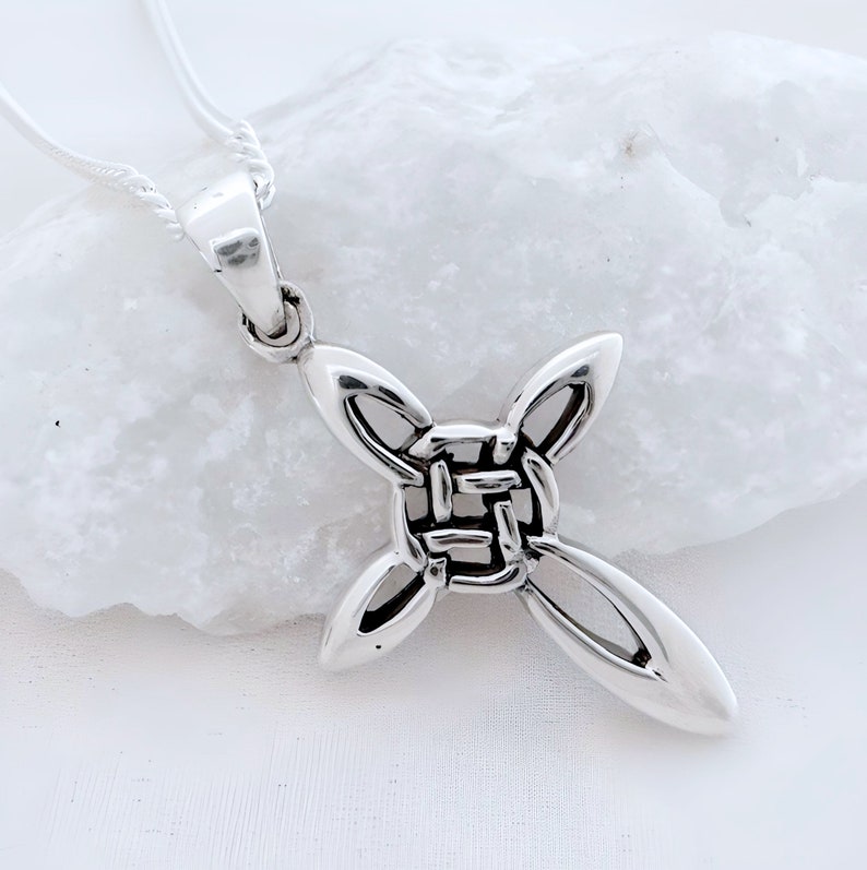 May include: Silver Celtic knot cross pendant necklace. The cross is made of a woven knot design with a smooth, polished finish.