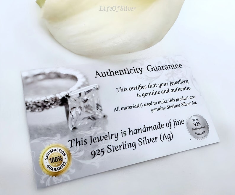 May include: A white card with the text "Authenticity Guarantee" and "This certifies that your Jewellery is genuine and authentic. All material(s) used to make this product are genuine Sterling Silver Ag. This Jewelry is handmade of fine 925 Sterling Silver (Ag)" printed on it. The card also has a small silver seal with the text "REAL 925 Sterling Silver Guarantee" printed on it.