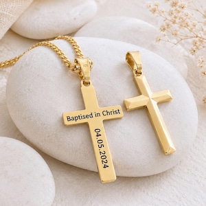 May include: Two gold-toned cross pendants, one attached to a matching chain. The left cross is engraved with the text "Baptised in Christ" horizontally and the date "04.05.2024" vertically. Both pendants feature a smooth, polished metallic finish.