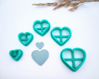 Puede incluir: Conjunto de seis cortadores de galletas en forma de corazón de color turquesa con un diseño de rejilla. Los cortadores están dispuestos en un degradado de tamaño, con el cortador más grande en la parte superior y el más pequeño en la parte inferior. También se incluye una galleta en forma de corazón de color turquesa en la imagen.