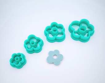 Puede incluir: Conjunto de cuatro cortadores de galletas en forma de flor de plástico turquesa de diferentes tamaños.