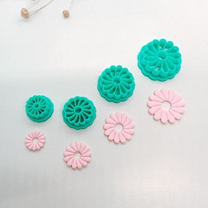 Op de afbeelding: Set van zes bloemvormige koekjesvormen in twee maten en twee kleuren. De grotere vormen zijn turquoisegroen en de kleinere zijn roze.