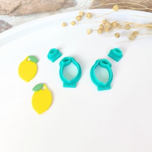 Puede incluir: Colección de cortadores de galletas amarillos con forma de limón y anillos turquesa. Los cortadores de limón tienen detalles de hojas verdes. Los cortadores turquesa tienen el texto "42C-G25" y "42F-D25".