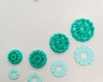 May include: Set of six teal-colored plastic flower-shaped cookie cutters of varying sizes.