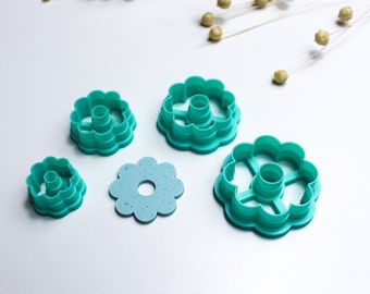 May include: Set of five turquoise plastic flower-shaped cookie cutters. The cutters are different sizes and have a variety of designs.