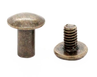 May include: Two antique brass colored metal screws with a round head and a threaded shaft. One screw has a flat head and the other has a domed head.