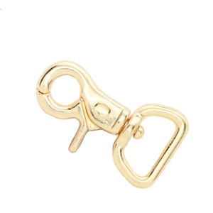 May include: Gold-toned metal swivel clasp with a D-ring. The clasp is designed to attach to a strap or chain.