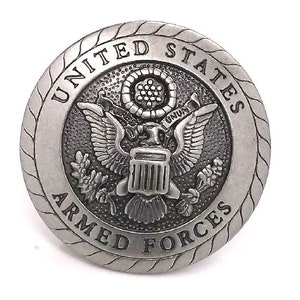 May include: A silver-toned metal button with a raised design of the United States Armed Forces seal. The seal features an eagle with outstretched wings, a shield with vertical stripes, and a banner with the word "E Pluribus Unum".