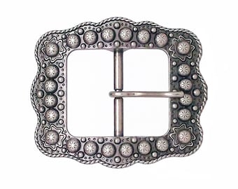Op de afbeelding: Een zilverkleurige metalen gesp met een decoratieve, gegolfde rand en een herhalend patroon van sterren en cirkels.