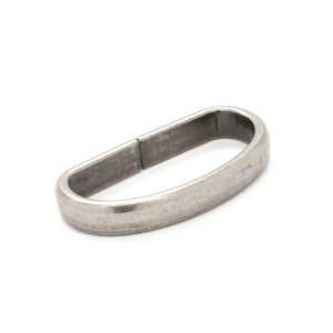 May include: Silver metal ring with a D-shaped opening. The ring is smooth and has a slightly textured finish.