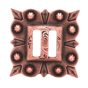 May include: A copper-colored metal buckle with a square frame and a double-loop design. The frame has a decorative pattern with small circles and points around the edges.