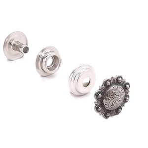 May include: Four silver metal snaps with a decorative design. The snaps are used for clothing and other crafts.