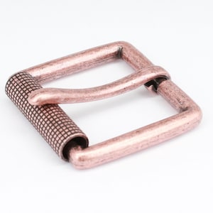 May include: A copper-toned metal belt buckle with a square shape and a textured, ridged design on the strap holder.