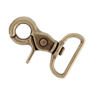 May include: Antique brass swivel clasp with a D-ring. This metal clasp is a great addition to any leather craft project.