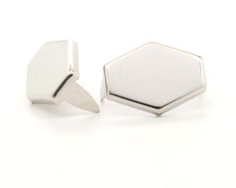 May include: Two silver-colored metal studs with a geometric design. One stud is a rectangular shape with a pointed post, and the other is a hexagon shape. The studs are on a white background.