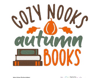 May include: Embroidered design with the text "Cozy Nooks Autumn Books" in orange and brown. A stack of books and a pumpkin with leaves are included in the design.