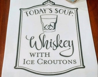 May include: White kitchen towel with black text that reads "Today's Soup: Whiskey with Ice Croutons". A glass of whiskey with ice is pictured above the text.