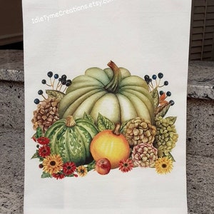May include: A white kitchen towel with a watercolor illustration of pumpkins, gourds, and fall flowers. The text "IdleTymeCreations.etsy.com" is printed in the top corner.