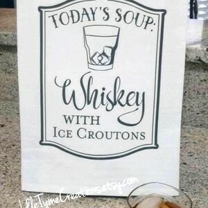 May include: A white kitchen towel with a black and white graphic that says "Today's Soup: Whiskey with Ice Croutons".