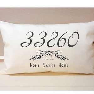 May include: White pillow with black text that reads "33860 Est. 2016 Home Sweet Home" with a decorative floral design.