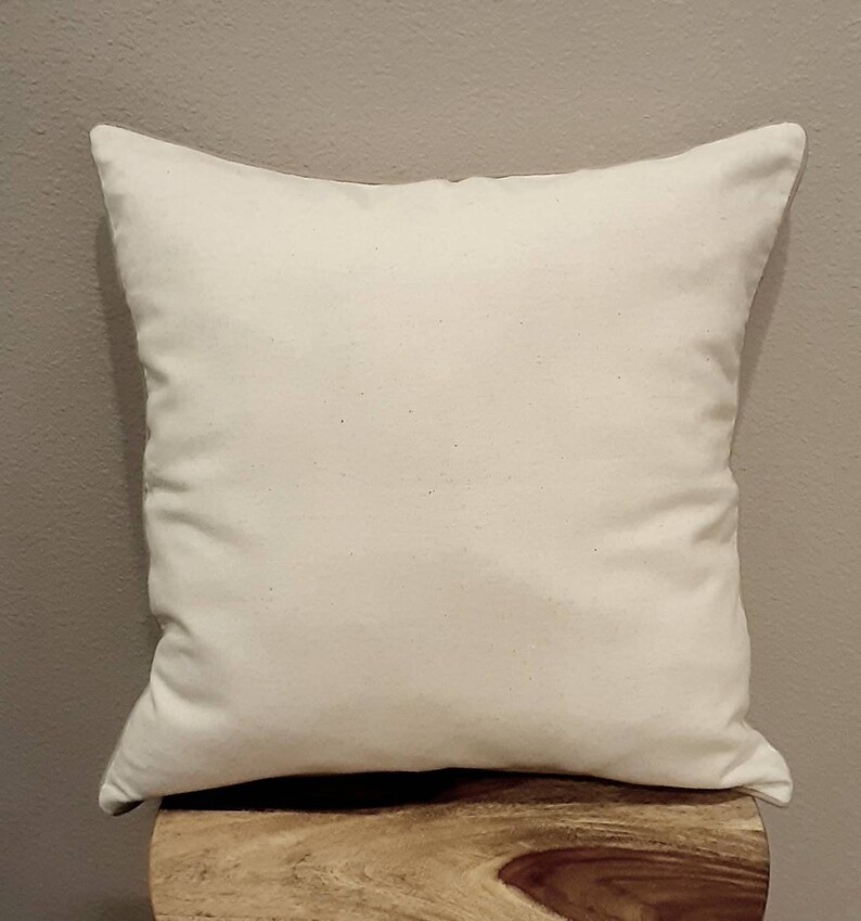May include: A plain white pillow with a smooth, even surface. The pillow is sitting on a wooden surface.
